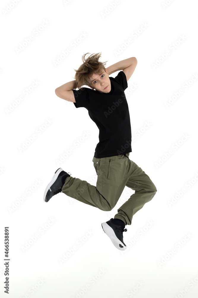 Isolated young Russian teenage boy in black t-shirt hip hop break dancer dancing in studio in white background, jumping and touching his head, looking into the camera