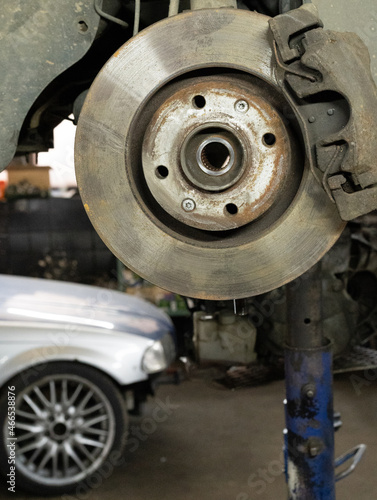 Disc brake of the vehicle for repair. Car brake repairing in garage.Suspension of car for maintenance brakes and shock absorber systems.Close up. Brake disc in the background.