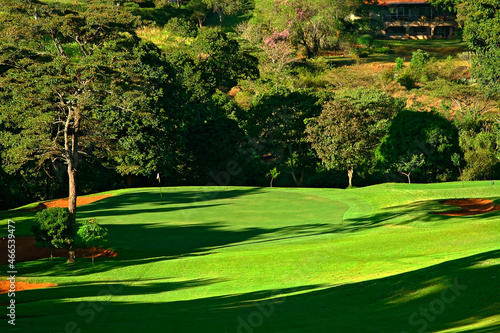 Parcours de golf, paysage avec arbres vert, ciel bleu et nuage blanc ainsi qu'un étang, lac.