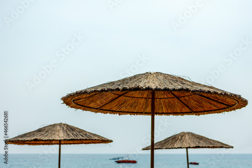 Fototapeta Naklejka Na Ścianę i Meble -  Large straw umbrellas on the beach against the background of the sea and sky.