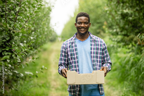 Satisfied farmer holding wooden box with crop