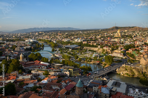Panoramic view of Tbilisi old town with Kura river (Mtkvari) and mountains on background in light of sunset. Famous georgian cityscape scene in Georgia.