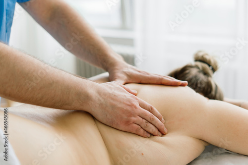 Young fat woman getting massage treatment in day spa cabinet.