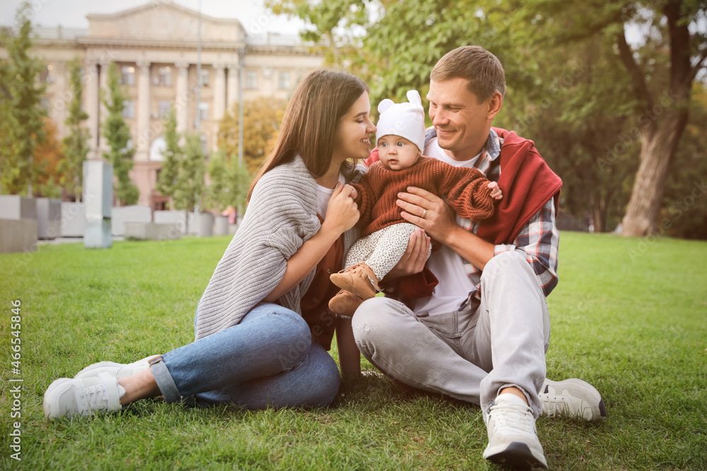 Happy parents with their adorable baby on green grass in park Happy parents with their adorable baby on green grass in park