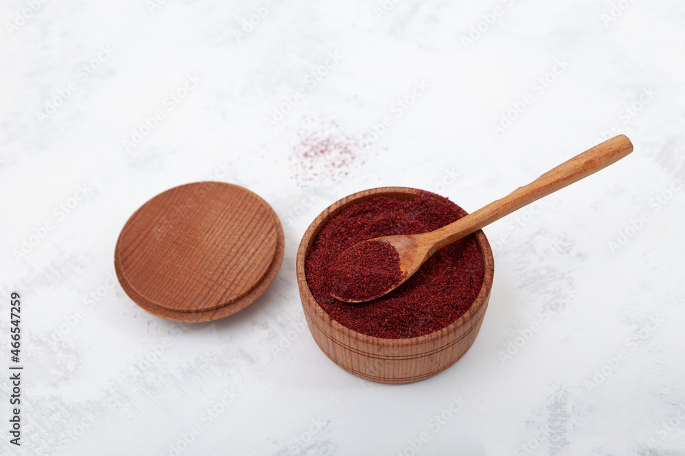 Dried ground red Sumac powder spices in wooden bowl. Sumac is spice