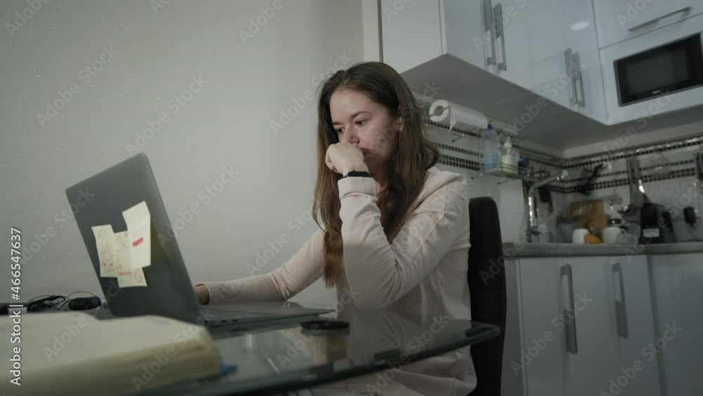 Focused young adult woman in casual clothes sitting on chair and using laptop while working on project in light modern apartment. Focused young adult woman in casual clothes sitting on chair and using laptop while working on project in light modern apartment.