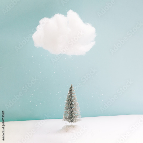 Winter polar night inspired concept. Minimal arrangement of one lonely tree with snowflakes falling from cloud.