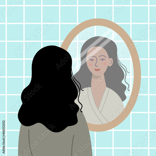 Black haired woman looking at herself in the mirror.