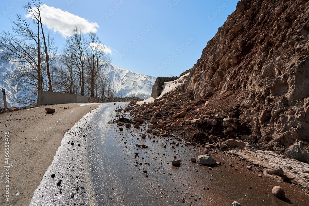 Early spring in the mountains. The rocks fell on the road. Dangerous bugle road. Rockfall in the mountains - obrazy, fototapety, plakaty 