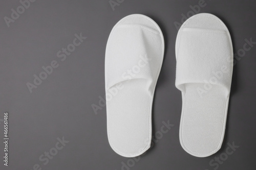 A pair of new terry slippers stand against a gray matte background. For home and hotels. Left place for text and editing