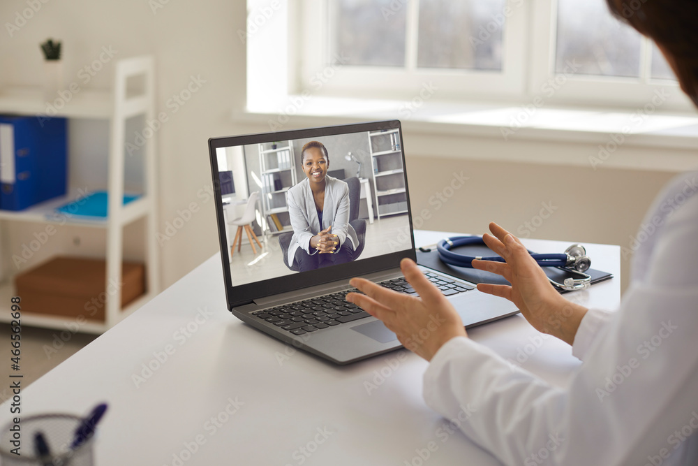 Online doctor sitting at table with laptop computer and stethoscope and counseling young female patient via video call. Telemedicine, professional online consultation, medical teleconference concept Online doctor sitting at table with laptop computer and stethoscope and counseling young female patient via video call. Telemedicine, professional online consultation, medical teleconference concept