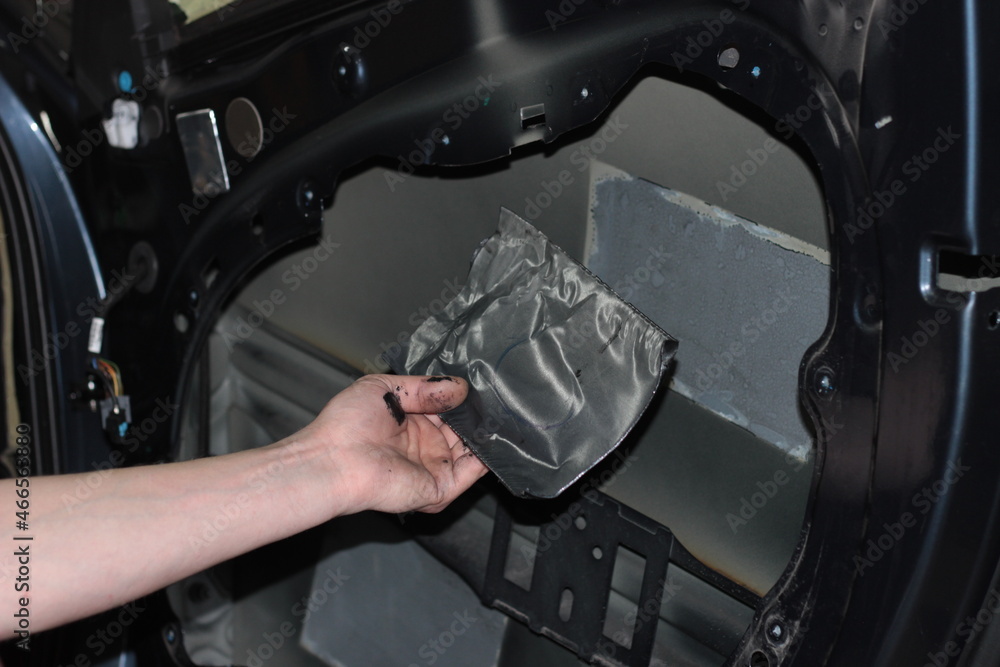 Car tuning. The man removes the vibration isolation from the car door