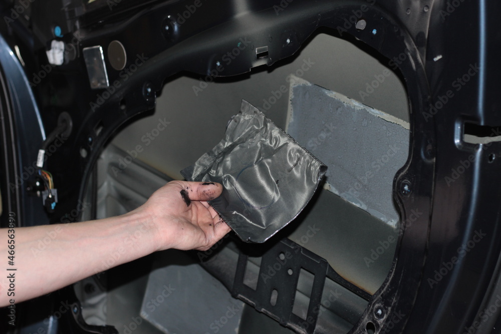 Car tuning. The man removes the vibration isolation from the car door