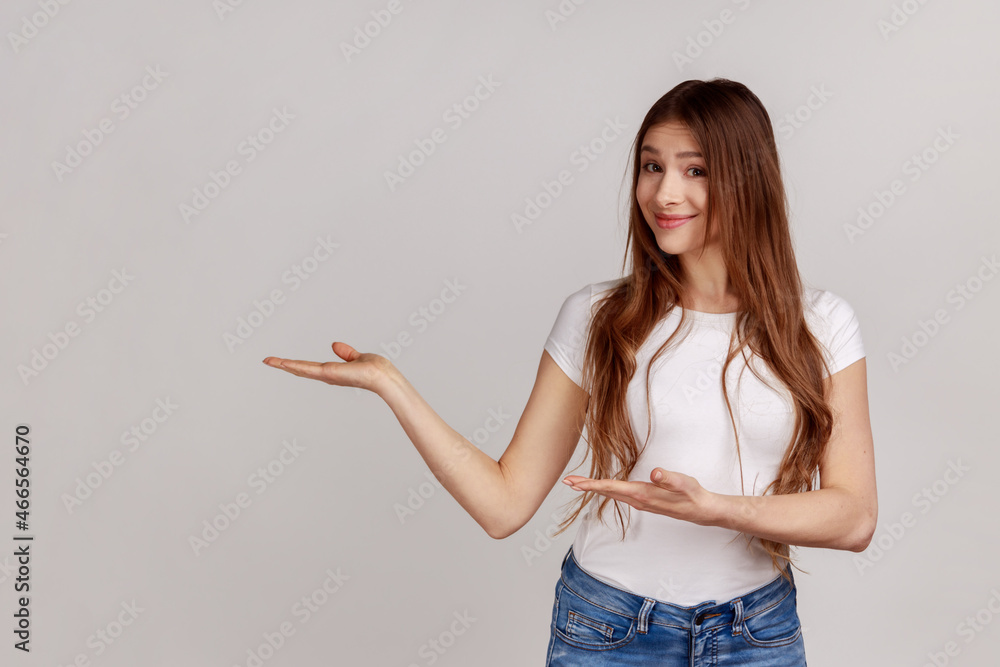 Please, take for free. Generous friendly pretty woman welcoming with wide open arms and smiling kindly, happy to embrace you, wearing white T-shirt. Indoor studio shot isolated on gray background. Please, take for free. Generous friendly pretty woman welcoming with wide open arms and smiling kindly, happy to embrace you, wearing white T-shirt. Indoor studio shot isolated on gray background.