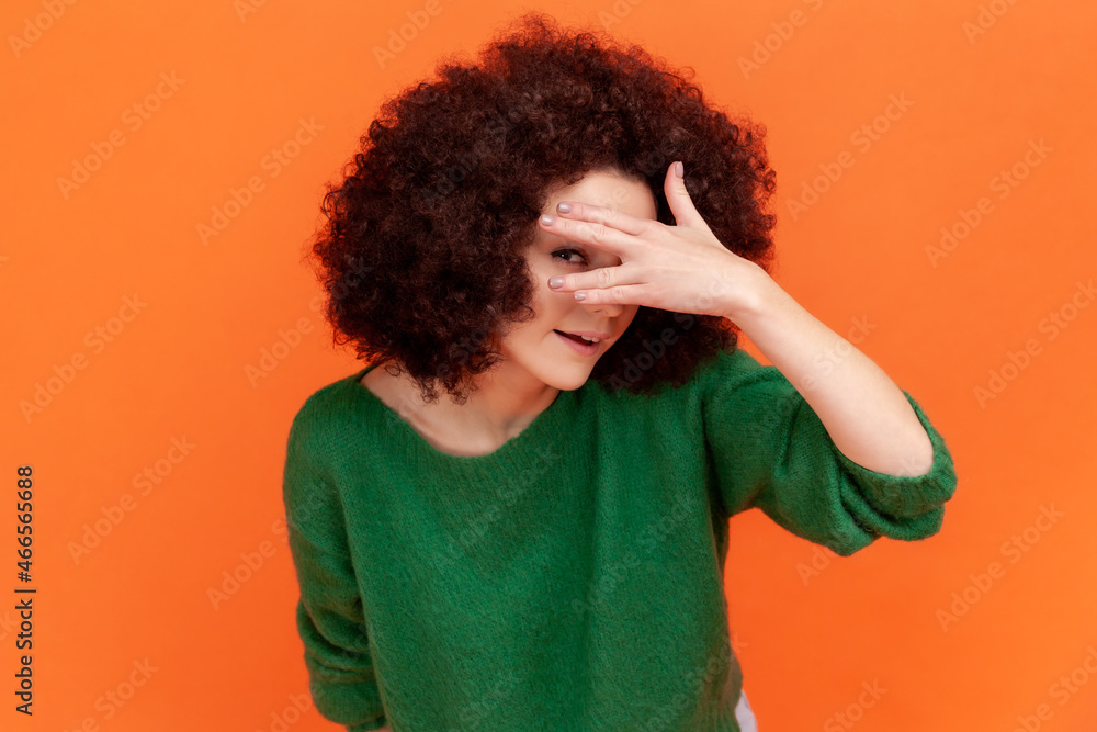 Φωτογραφία Curious woman with Afro hairstyle wearing green casual style sweater spying, hiding and peeping through fingers, looking for secrets, curiosity