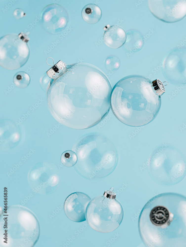 Creative Christmas composition with transparent glass ornaments and soap bubbles flying on pastel blue background. Minimal Xmas or New Year celebration concept. Minimal winter holidays idea.