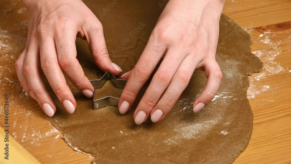 Closeup of a woman making star shaped forms from gingerbread dough for baking cookies for christmas Closeup of a woman making star shaped forms from gingerbread dough for baking cookies for christmas