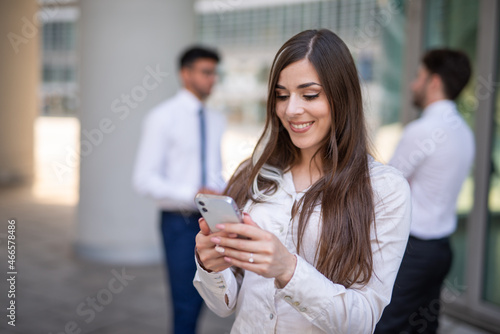 Businesswoman using her smartphone in front of her office