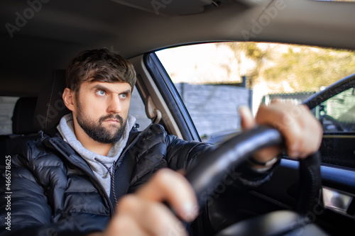 a bearded man sits in the passenger compartment and holds the steering wheel.