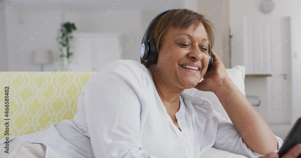 Happy african american senior woman wearing headphone enjoying using smartphone and smiling Happy african american senior woman wearing headphone enjoying using smartphone and smiling