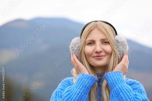 Young beautiful woman wearing warm earmuffs in mountains