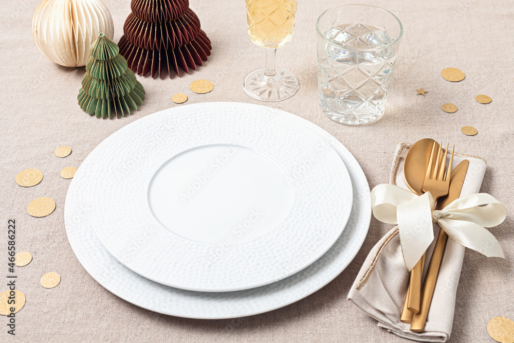Festive christmas table setting with golden cutlery and porcelain plate and christmas decoration. Mockup for place card, dinner invitation, restaurant menu template. Copy space Festive christmas table setting with golden cutlery and porcelain plate and christmas decoration. Mockup for place card, dinner invitation, restaurant menu template. Copy space