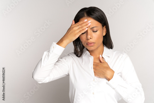 Woman has covid-19 symptoms: breathing difficulties, fever and shortness of breath. Tired unhealthy woman with chest pain and headache suffer from migraine or stress, panic attack touching forehead photo