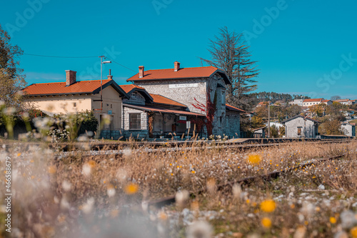 Train station of Stanjel visible on a warm autumn day, with flowers in the foreground of the train tracks and platform. Stanjel city in the background photo