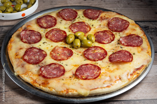 pizza recien horneada con rodajas de salame y queso caliente