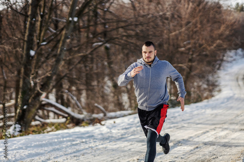 Fast sportsman sprinting in forest at snowy winter day, Cardio exercises, winter fitness © dusanpetkovic1