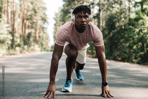 Fit black male sprinter, in starting position ready to run, Male athlete about to start sprint outdoors in the forest