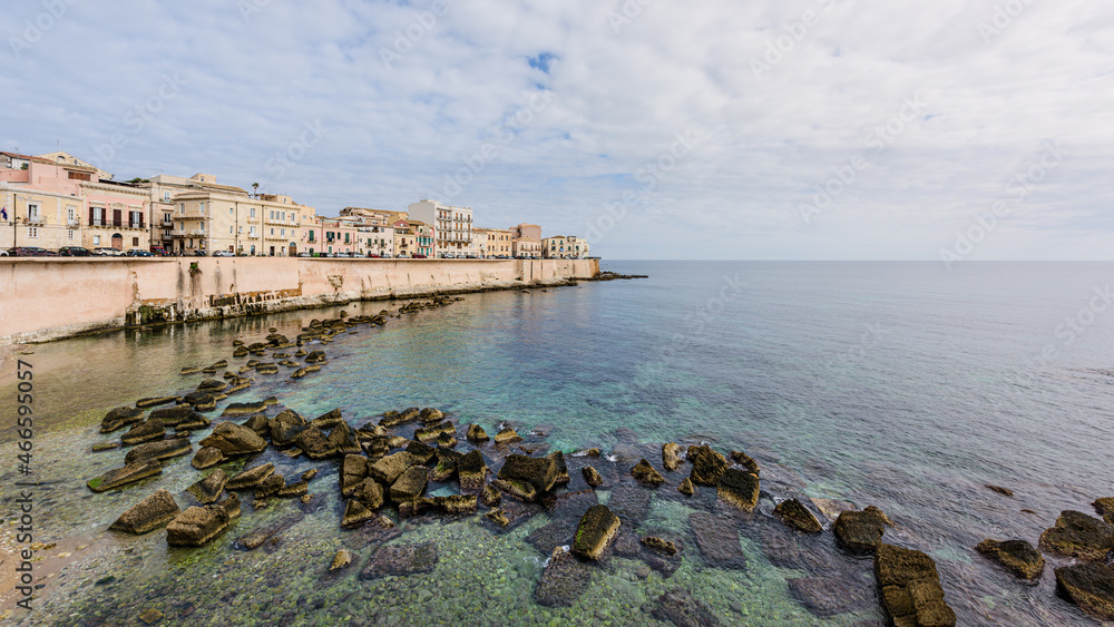 Sunrise on the coast of Ortigia, a travel destination and an ancient Greek city in Syracuse, Sicily, Italy, with the old medieval town and the Mediterranean sea front