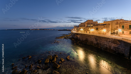 Sunset on the coast of Ortigia, a travel destination and an ancient Greek city in Syracuse, Sicily, Italy, with the old medieval town and the Mediterranean sea shore