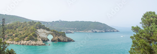 Panorama seascape of Apulian coastline with natural arch formation and tourist boats in Adriatic sea, Gargano national park, a famous place in Puglia, Italy
