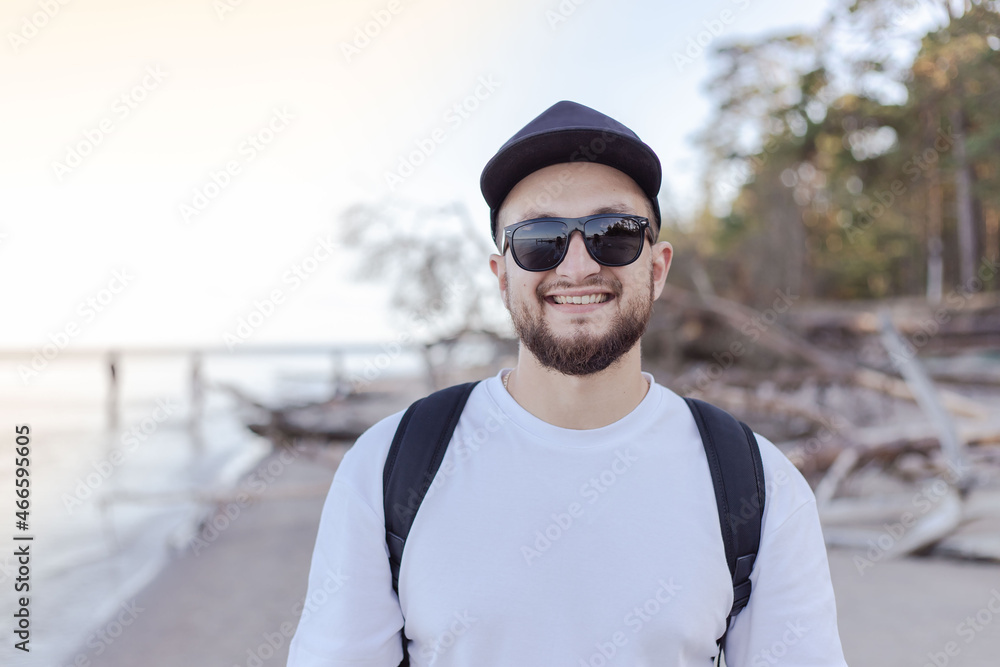 Smiling handsome young man with backpack standing on the beach. Smiling handsome young man with backpack standing on the beach.