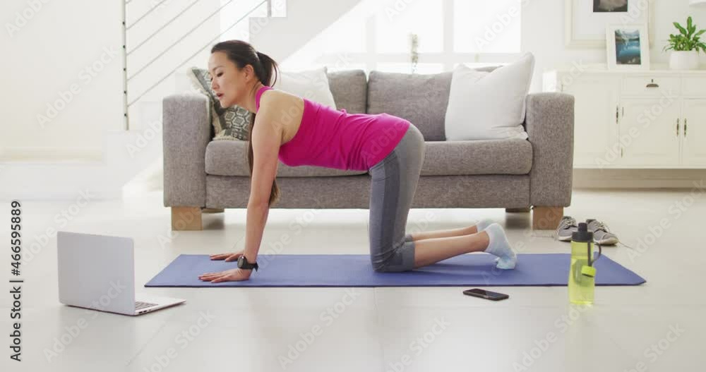 Asian woman on mat exercising with laptop at home Asian woman on mat exercising with laptop at home