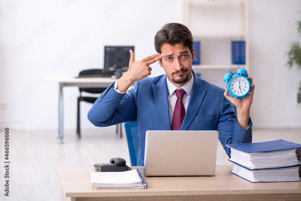 Young male employee in time management concept Young male employee in time management concept