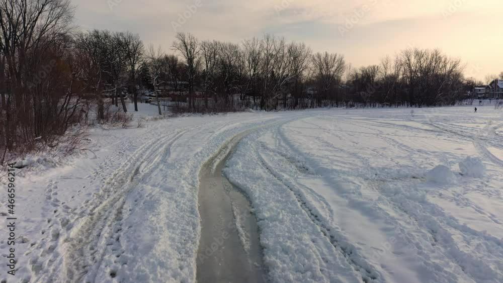Flying with a drone at a low angle following the tire tracks in the snow and revealing the ice underneath at Berges-des-quatre-vents in laval-Ouest Flying with a drone at a low angle following the tire tracks in the snow and revealing the ice underneath at Berges-des-quatre-vents in laval-Ouest