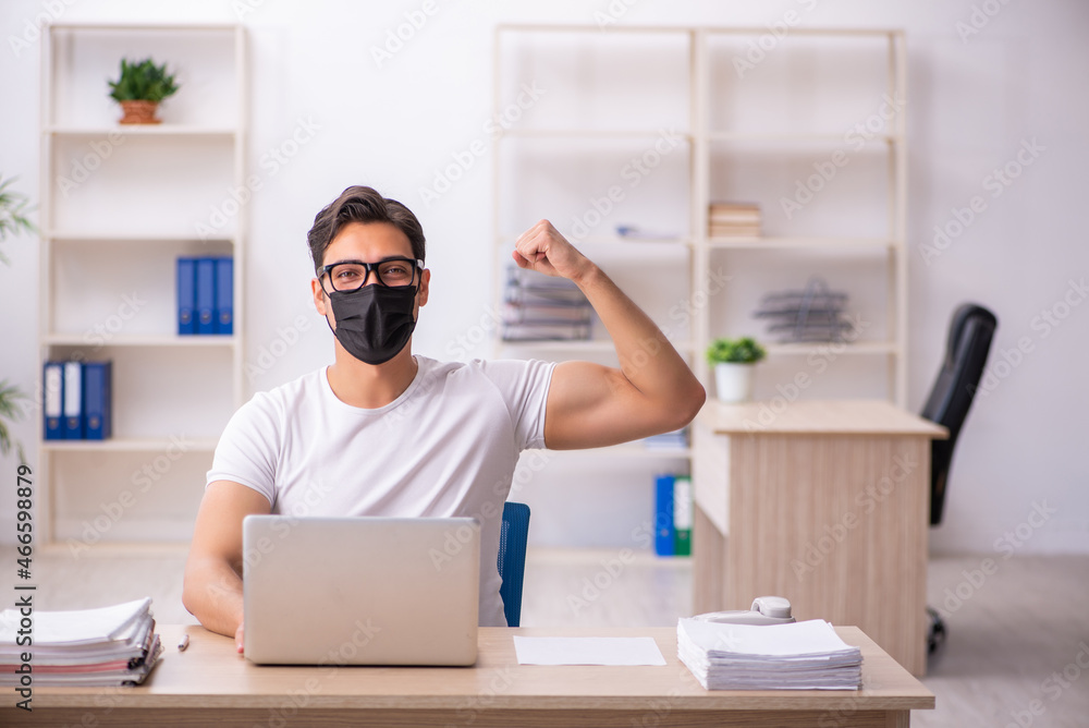 Young male student employee working at workplace during pandemic Young male student employee working at workplace during pandemic