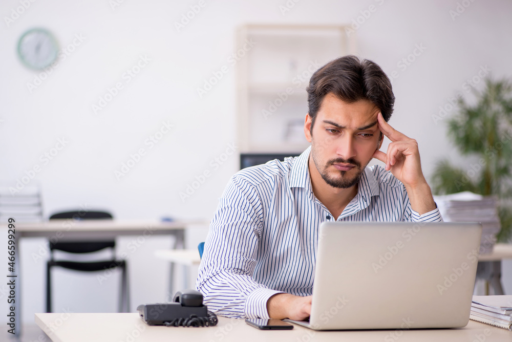 Young male employee and too much work in the office Young male employee and too much work in the office