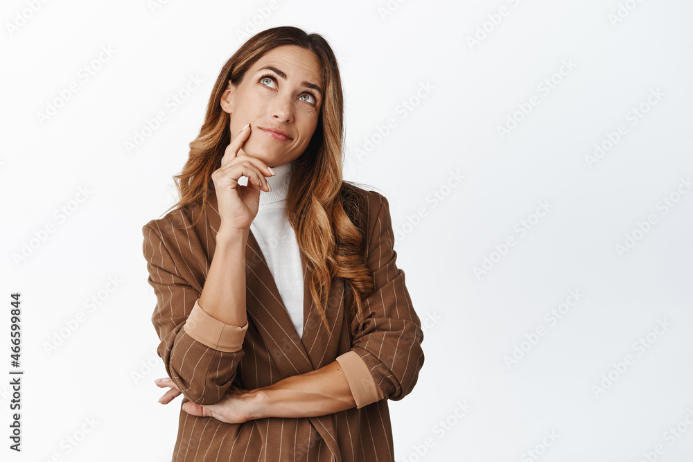 Image of thoughtful corporate woman looking up, pondering something, thinking, standing against white background Image of thoughtful corporate woman looking up, pondering something, thinking, standing against white background