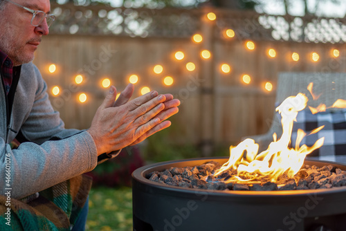 Man warming his hands by a fire in fall
