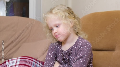 a cute girl with curly blond hair was offended and puffed out her cheeks, a disgruntled Caucasian girl on a chair