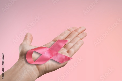 Persons hand holding the pink ribbon in palm symbol of breast cancer awareness