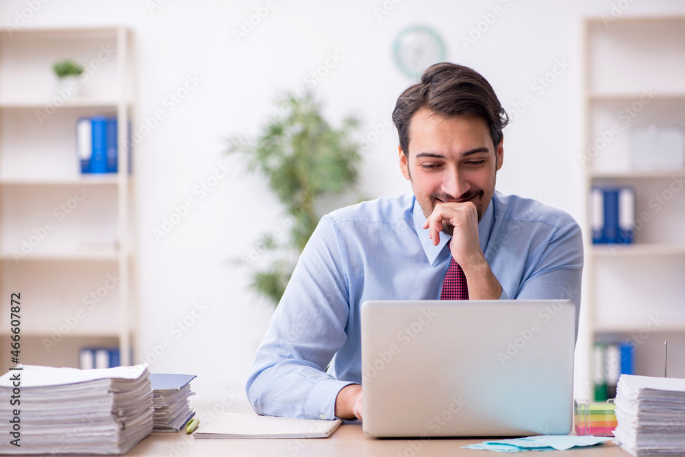 Young male employee and too much work in the office Young male employee and too much work in the office
