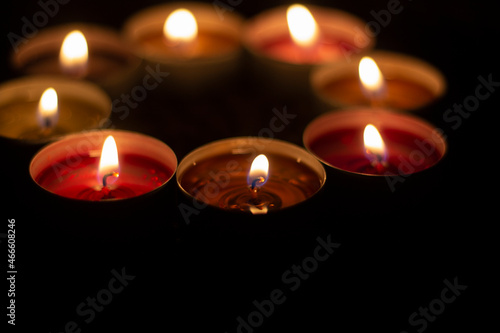 Candles are collected in a circle. A circle of wax candles. Liquid wax orange and red. Romantic atmosphere with open fire in the dark.