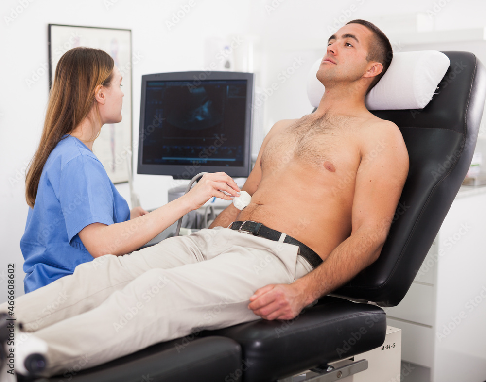 Obraz premium Young woman doctor and patient during the ultrasound examination of abdomen in medical office