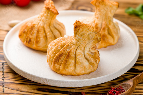 Fried Georgian khinkali on white plate on wooden table