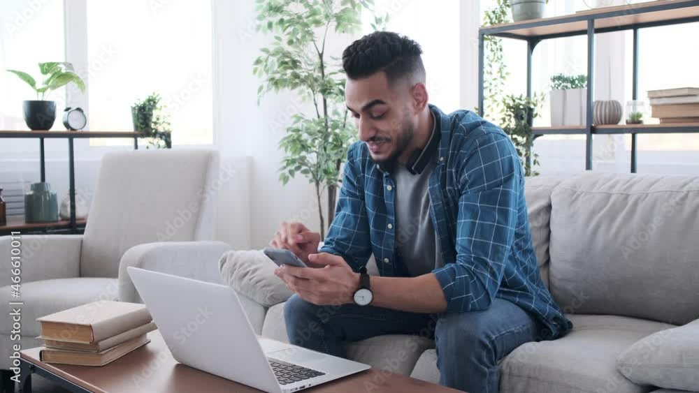 Happy man using mobile phone with laptop on table at home Happy man using mobile phone with laptop on table at home