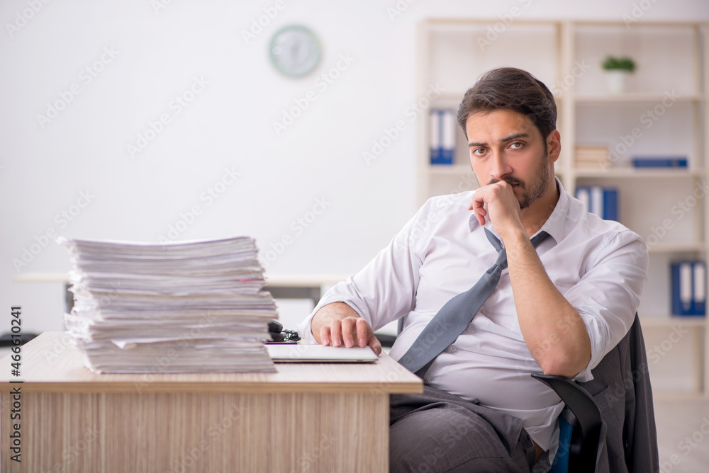 Naklejka premium Young male employee and too much work in the office